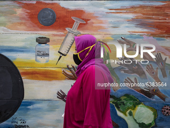 A woman passing by the mural Covid19 in Tangerang, Banten, Indonesia, on 26 January 2021. Indonesia reach out to 1 million of Covid19 positi...