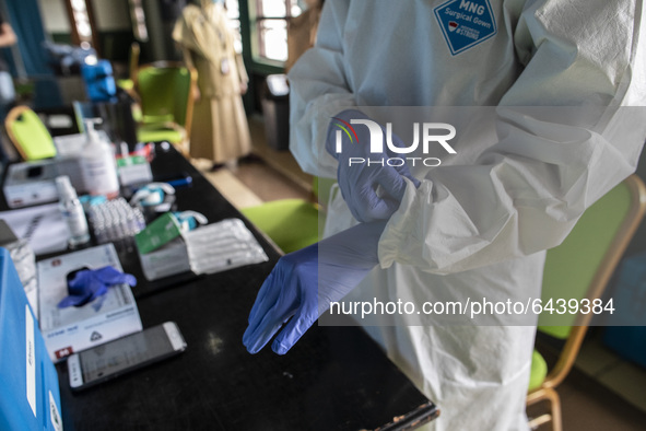  Vaccinator put on her gloves. 2nd Phase of Vaccination covid19 for health worker in Indonesia held at one of location at Health Dipoloma Ed...