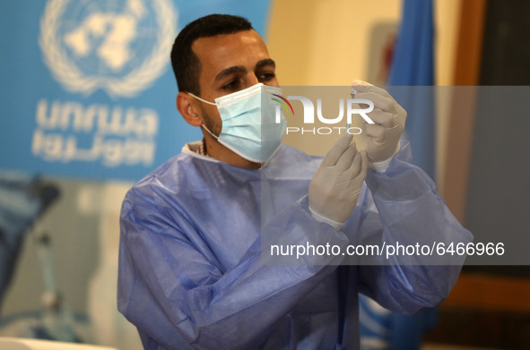 A Palestinian health worker prepares to vaccinate Matthias Schmale, UNRWA's Gaza director, against the coronavirus disease (COVID-19), 