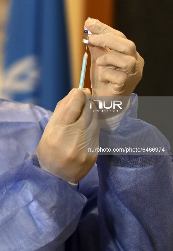 A Palestinian health worker prepares to vaccinate Matthias Schmale, UNRWA's Gaza director, against the coronavirus disease (COVID-19), 