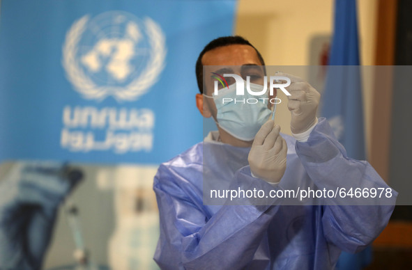 A Palestinian health worker prepares to vaccinate Matthias Schmale, UNRWA's Gaza director, against the coronavirus disease (COVID-19), 