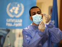 A Palestinian health worker prepares to vaccinate Matthias Schmale, UNRWA's Gaza director, against the coronavirus disease (COVID-19), (