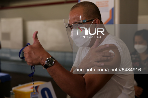 A man gives the thumbs up sign after getting inoculated with the Sinovac COVID19 vaccine during a ceremonial vaccination program held inside...