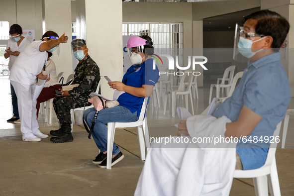 A nurse assists a member of the Philippine Navy after getting inoculated with the Sinovac COVID19 vaccine during a ceremonial vaccination pr...