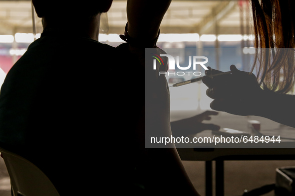 A nurse administers the Sinovac COVID19 vaccine during a ceremonial vaccination program held inside a sports stadium in Marikina City, east...