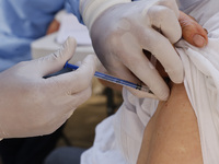 A person receives a dose of Pfizer-BioNTech Covid-19 vaccine before inject to an elderly, during mass vaccine inside of Hermanos Lopez Rayon...