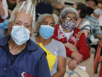 Persons wait  receive  a dose of Pfizer-BioNTech Covid-19 vaccine   during mass vaccine inside of Hermanos Lopez Rayon sports center, a desi...