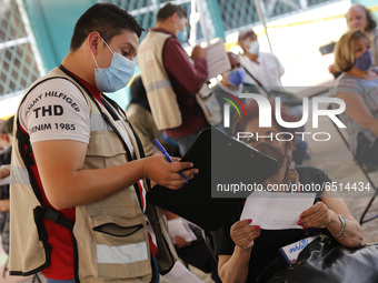 A elderly fill out a form after receive a dose of Pfizer-BioNTech Covid-19 vaccine, during mass vaccine inside of Hermanos Lopez Rayon sport...