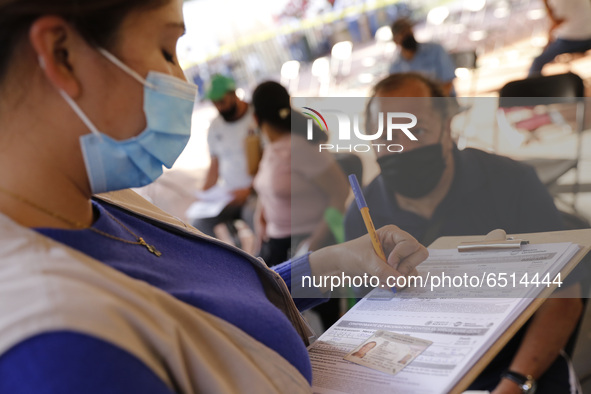 A elderly fill out a form after receive a dose of Pfizer-BioNTech Covid-19 vaccine, during mass vaccine inside of Hermanos Lopez Rayon sport...