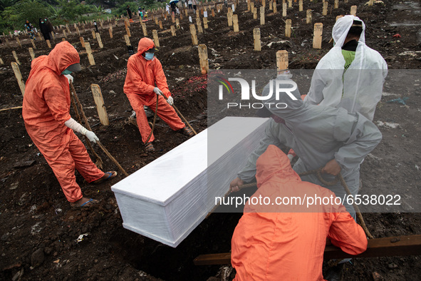 Grave digger put coffin to the grave.  Burrial process of a victim of Covid19 at Srengsawah, South Jakarta, Indonesia on March 19, 2021. Num...