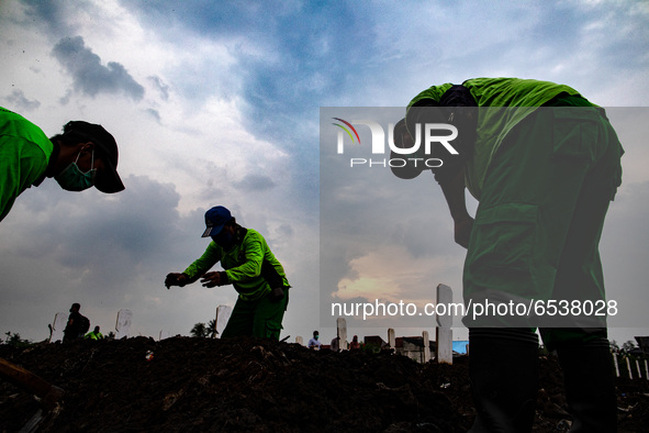 Grave digger finlallize the grave for family to put flower on top. Burrial process of a victim of Covid19 at Srengsawah, South Jakarta, Indo...