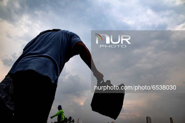 Jakarta, Indonesia, 19 march 2021 :A family member with flowers in the plastic to say last good bye.  Burrial process of a victim of Covid19...