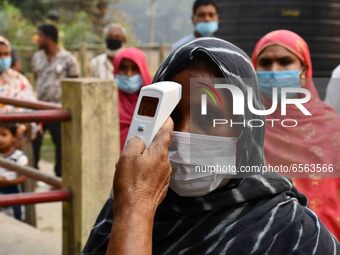 A health worker checks the body temperature of a voter, as a preventive measure against the COVID-19 coronavirus, before casting her ballot...