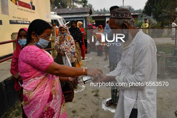 Voters uses hand sanitizer   during the first phase  during the first phase of  polling  for Assam Assembly Elections, at Rupohi   constitue...