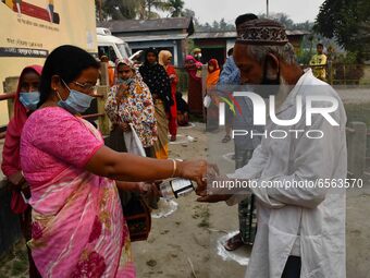 Voters uses hand sanitizer   during the first phase  during the first phase of  polling  for Assam Assembly Elections, at Rupohi   constitue...