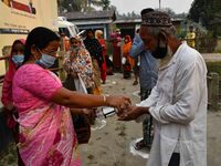 Voters uses hand sanitizer   during the first phase  during the first phase of  polling  for Assam Assembly Elections, at Rupohi   constitue...