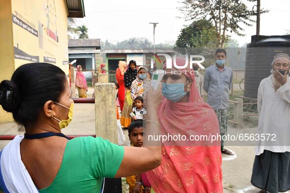 A health worker checks the body temperature of a voter, as a preventive measure against the COVID-19 coronavirus, before casting her ballot...