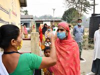 A health worker checks the body temperature of a voter, as a preventive measure against the COVID-19 coronavirus, before casting her ballot...