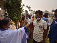 A health worker checks the body temperature of a voter, as a preventive measure against the COVID-19 coronavirus, before casting her ballot...