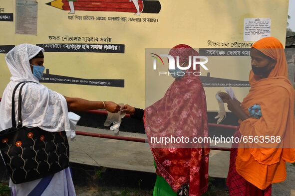 Voters put on gloves as part of precautions against COVID-19 while waiting to cas votes at a polling station, during the first phase of poll...