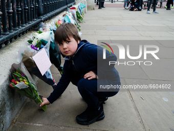 Boy lays down a bouquet of flowers outside Buckingham Palace after it was announced that Britain's Prince Philip, husband of Queen Elizabeth...