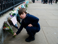 Boy lays down a bouquet of flowers outside Buckingham Palace after it was announced that Britain's Prince Philip, husband of Queen Elizabeth...