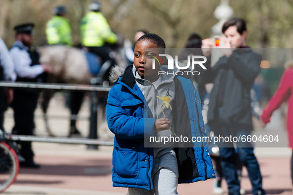 Boy lays down a bouquet of flowers outside Buckingham Palace after it was announced that Britain's Prince Philip, husband of Queen Elizabeth...