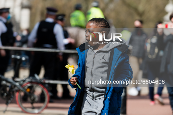 Boy lays down a bouquet of flowers outside Buckingham Palace after it was announced that Britain's Prince Philip, husband of Queen Elizabeth...