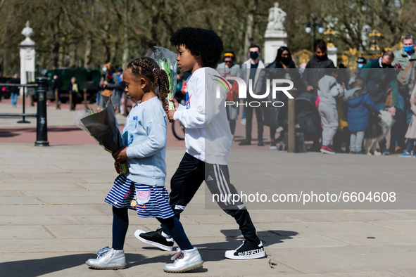 Girl and a boy lays down a bouquet of flowers outside Buckingham Palace after it was announced that Britain's Prince Philip, husband of Quee...