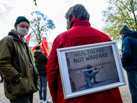 A woman is carrying a placard on her back, in support of the healthcare system, during the International Worker's Day demonstration held in...