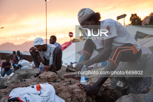 Migrants wash themselves with water bottles near the sea; in the city of Ventimiglia, on the French-Italian border, on June 23; 2015. The si...