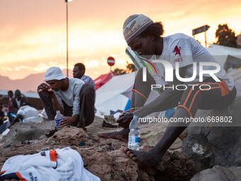 Migrants wash themselves with water bottles near the sea; in the city of Ventimiglia, on the French-Italian border, on June 23; 2015. The si...