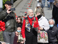 People carry flowers to the Monument of Eternal Glory on the Tomb of the Unknown Soldier, during the Victory Day celebration amid the Covid-...