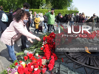 People carry lay flowers to the Monument of Eternal Glory on the Tomb of the Unknown Soldier, during the Victory Day celebration amid the Co...
