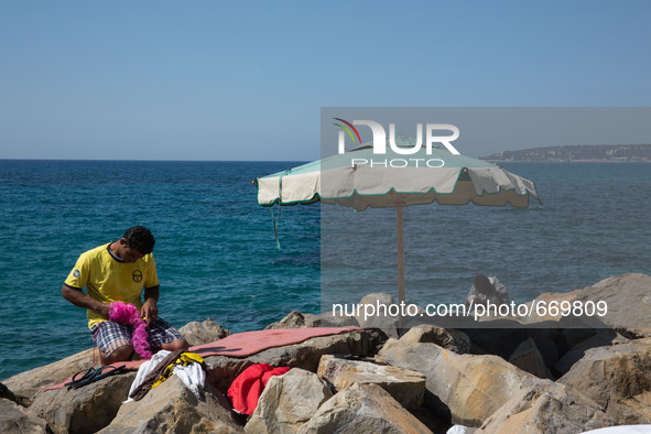 Migrants wait near the sea, in the city of Ventimiglia at the French-Italian border, on June 24, 2015. The situation of migrants camped in V...