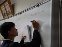 Pictures of Kim Il Sung and Kim Jong Il hang on the wall as a student solve a math quiz on a whiteboard during a math class at Hiroshima Kor...