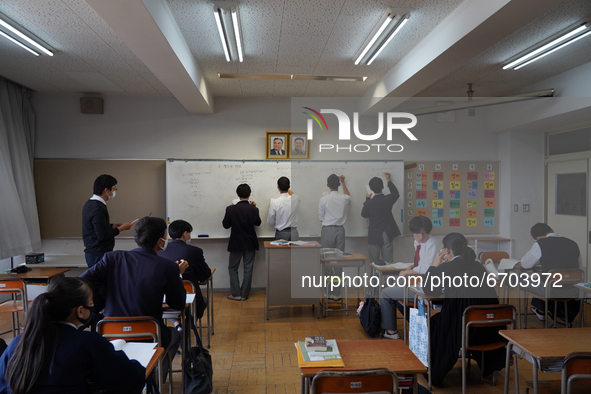 Pictures of Kim Il Sung and Kim Jong Il hang on the wall as students solve math quizzes on a whiteboard in a math class at Hiroshima Korean...