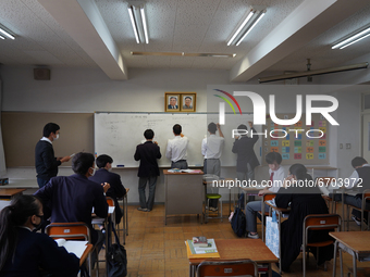 Pictures of Kim Il Sung and Kim Jong Il hang on the wall as students solve math quizzes on a whiteboard in a math class at Hiroshima Korean...