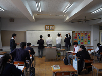 Pictures of Kim Il Sung and Kim Jong Il hang on the wall as students solve math quizzes on a whiteboard in a math class at Hiroshima Korean...