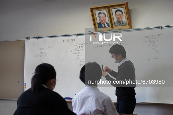 Pictures of Kim Il Sung and Kim Jong Il hang on the wall as a teacher conducts a math lecture at Hiroshima Korean School on May 9, 2021 in H...