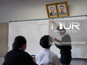 Pictures of Kim Il Sung and Kim Jong Il hang on the wall as a teacher conducts a math lecture at Hiroshima Korean School on May 9, 2021 in H...