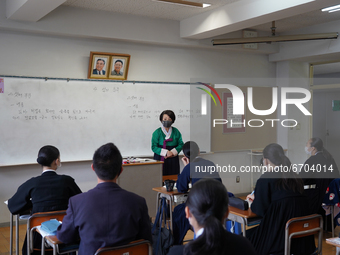 Pictures of Kim Il Sung and Kim Jong Il hang on the wall as a teacher wearing a traditional dress conducts a Korean lecture at Hiroshima Kor...