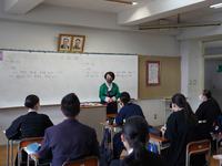 Pictures of Kim Il Sung and Kim Jong Il hang on the wall as a teacher wearing a traditional dress conducts a Korean lecture at Hiroshima Kor...