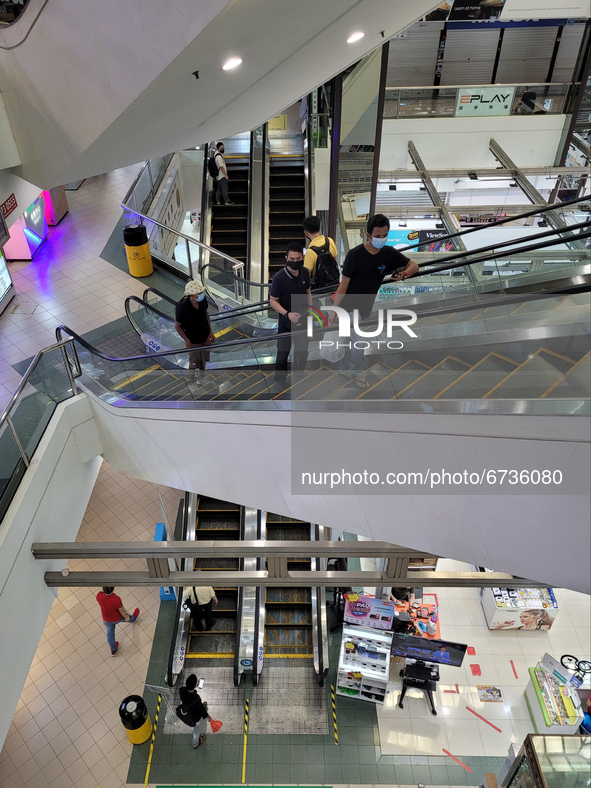 Shoppers wearing masks ride escalators in a Shopping mall in Singapore days after new lockdown measures were announced after a spike in Covi...