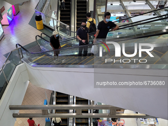 Shoppers wearing masks ride escalators in a Shopping mall in Singapore days after new lockdown measures were announced after a spike in Covi...