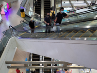 Shoppers wearing masks ride escalators in a Shopping mall in Singapore days after new lockdown measures were announced after a spike in Covi...