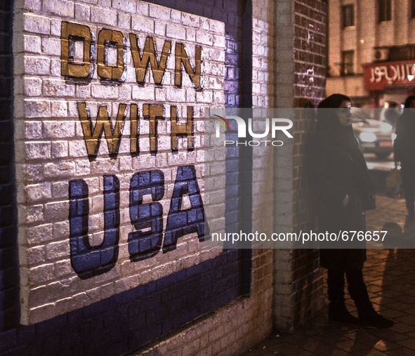 "Down with USA" on the wall of the old closed US embassy in Tehran and waiting woman.

 