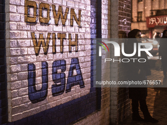 "Down with USA" on the wall of the old closed US embassy in Tehran and waiting woman.

 (