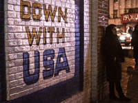 "Down with USA" on the wall of the old closed US embassy in Tehran and waiting woman.

 (