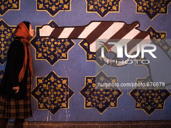 Symbolic portrait of young woman giving a kiss to a gun painted in the colors of USA on old closed US embassy in Tehran.

 (